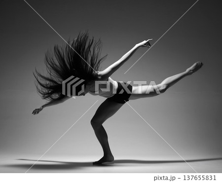 Dancer performs a dynamic movement in a studio with dramatic lighting and high contrast colors 137655831
