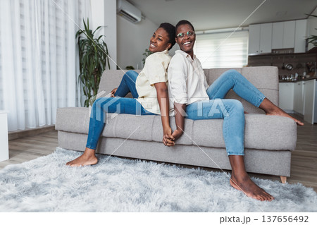 Two Young Women Holding Hands and Relaxing on Sofa at Home Two Young Women Holding Hands and Relaxing on Sofa at Home 137656492