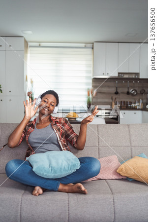 Young woman enjoying music with headphones in living room Young woman enjoying music with headphones in living room 137656500