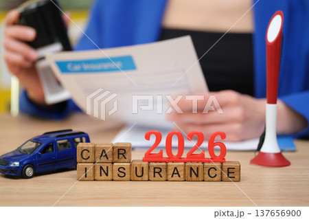 Reviewing car insurance documents for 2026 while surrounded by paperwork and a toy vehicle 137656900