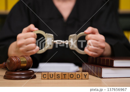 Judge holds handcuffs while discussing custody during court proceedings in a solemn environment 137656967