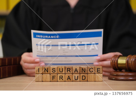 Courtroom scene featuring a judge evaluating an important document on insurance fraud Courtroom scene featuring a judge evaluating an important document on insurance fraud 137656975