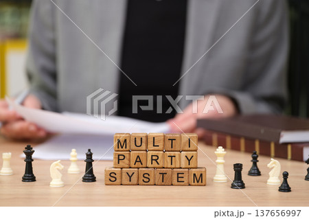 Chess pieces and wooden blocks highlight the concept of a multi-party system during a political discussion at a cozy desk Chess pieces and wooden blocks highlight the concept of a multi-party system during a political discussion at a cozy desk 137656997