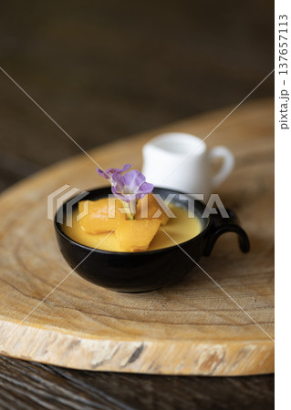 mango mousse pudding in a cup sits on a table  137657113