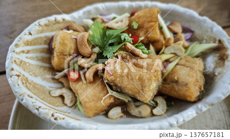 Crispy fried sea bass with a rich, spicy and sour spiced sauce and herbs. 137657181