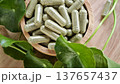 Herbal capsules containing Centella asiatica powder in a wooden bowl. A natural dietary supplement. 137657437