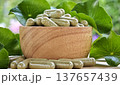 Herbal capsules containing Centella asiatica powder in a wooden bowl. A natural dietary supplement. 137657439