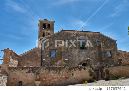 Ancient stone church of San Juan Bautista in Pedraza, Segovia, under clear skies 137657642