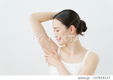 白背景の脇に手を当てて微笑む若い日本人女性 脱毛イメージ 白背景の脇に手を当てて微笑む若い日本人女性 脱毛イメージ 137658137