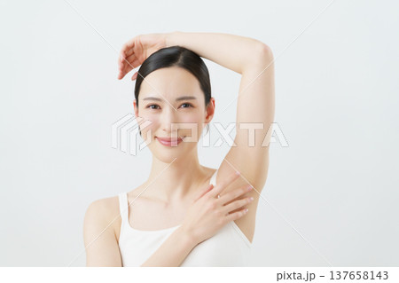 白背景の脇に手を当てて微笑む若い日本人女性　脱毛イメージ 137658143
