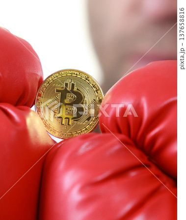 Man in boxing gloves holding bitcoin Man in boxing gloves holding bitcoin 137658816