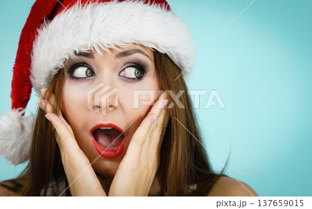 Surprised woman in santa claus hat 137659015