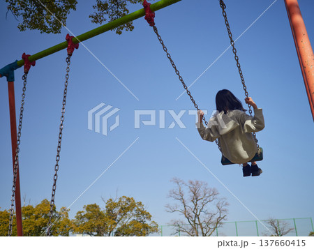 春の昼の公園で楽しくブランコで遊んでいる十代の女の子の姿 春の昼の公園で楽しくブランコで遊んでいる十代の女の子の姿 137660415