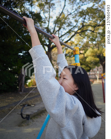 春の昼の公園で楽しく鉄棒で遊んでいる十代の女の子の姿 春の昼の公園で楽しく鉄棒で遊んでいる十代の女の子の姿 137660493