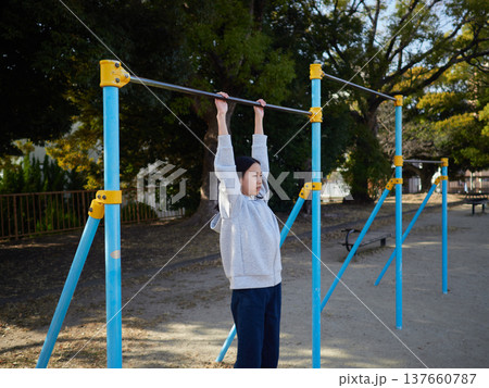 春の昼の公園で楽しく鉄棒で遊んでいる十代の女の子の姿	 137660787