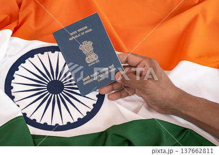 Holding an OCI card in a hand with National Indian flag on the background. Holding an OCI card in a hand with National Indian flag on the background. 137662811