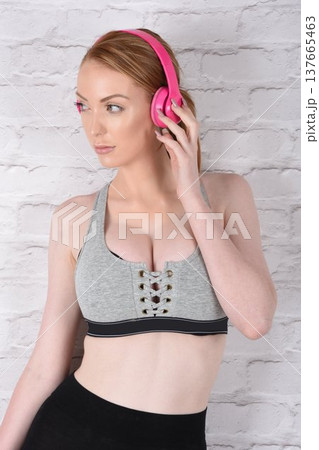 Tall, attractive redhead girl in black leggings and a grey sports bra, exercising at the gym 137665463