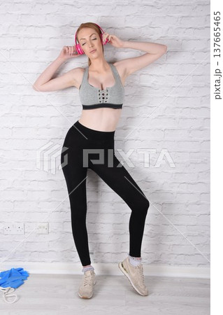 Tall, attractive redhead girl in black leggings and a grey sports bra, exercising at the gym Tall, attractive redhead girl in black leggings and a grey sports bra, exercising at the gym 137665465