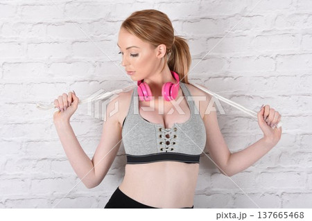 Tall, attractive redhead girl in black leggings and a grey sports bra, exercising at the gym 137665468