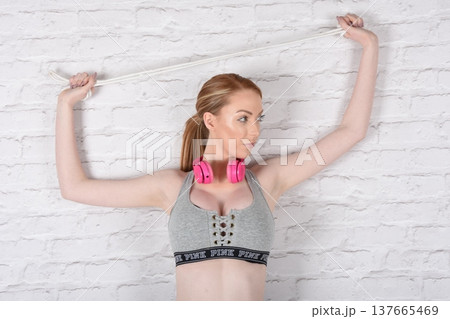 Tall, attractive redhead girl in black leggings and a grey sports bra, exercising at the gym Tall, attractive redhead girl in black leggings and a grey sports bra, exercising at the gym 137665469