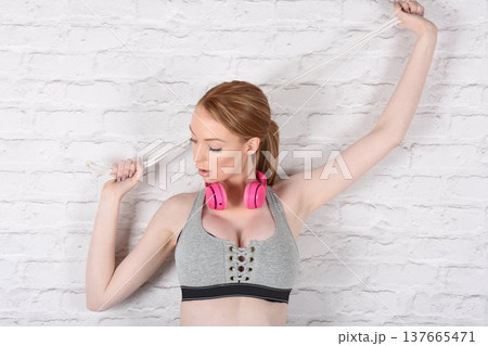 Tall, attractive redhead girl in black leggings and a grey sports bra, exercising at the gym 137665471