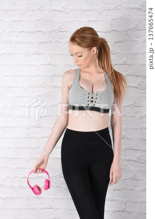 Tall, attractive redhead girl in black leggings and a grey sports bra, exercising at the gym 137665474