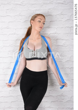 Tall, attractive redhead girl in black leggings and a grey sports bra, exercising at the gym 137665476