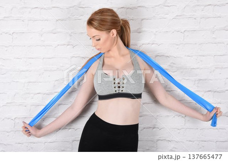 Tall, attractive redhead girl in black leggings and a grey sports bra, exercising at the gym 137665477