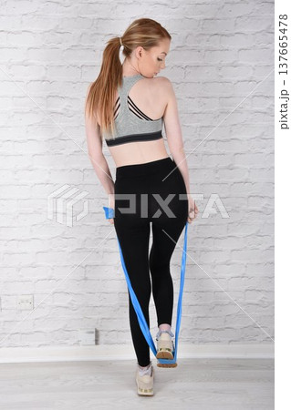 Tall, attractive redhead girl in black leggings and a grey sports bra, exercising at the gym Tall, attractive redhead girl in black leggings and a grey sports bra, exercising at the gym 137665478
