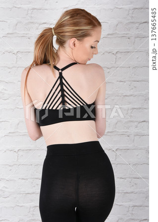 Tall, attractive redhead girl in black leggings and a grey sports bra, exercising at the gym 137665485