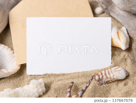 Blank card mockup on sand with seashells and driftwood, beach wedding and summer event invitation Blank card mockup on sand with seashells and driftwood, beach wedding and summer event invitation 137667079