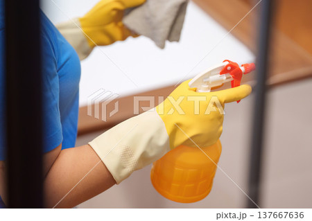 Home Cleaning. Close-up of a woman holding a spray bottle while cleaning. Home Cleaning. Close-up of a woman holding a spray bottle while cleaning. 137667636