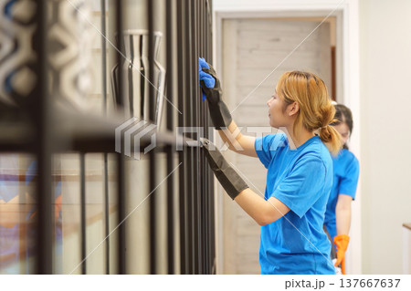 Team Cleaning. Two women dusting shelves in a modern interior. Team Cleaning. Two women dusting shelves in a modern interior. 137667637