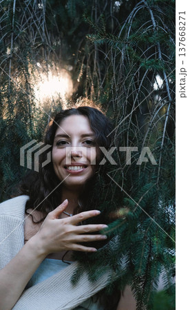 Portrait of a very beautiful young woman in a summer spruce forest at sunset. 137668271