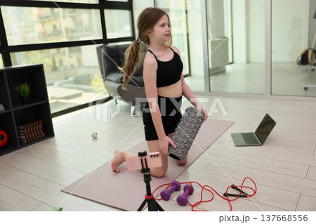 Young girl practices yoga and fitness at home with colorful equipment on a sunny day 137668556