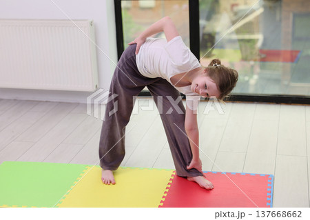 Young girl practicing yoga and stretching in a bright exercise studio with colorful mats during a calm afternoon Young girl practicing yoga and stretching in a bright exercise studio with colorful mats during a calm afternoon 137668662