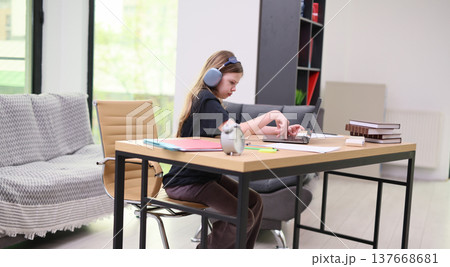 Focused student engaged in homework at a modern workspace with natural light and cozy decor 137668681
