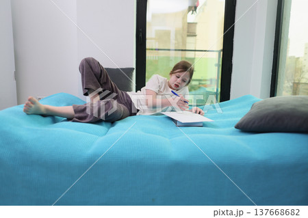 Creating art in a cozy corner with soft blue blankets and natural light filling the room 137668682