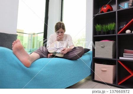 Exciting moment unfolds as a young girl discovers a surprise gift at home during a cozy afternoon Exciting moment unfolds as a young girl discovers a surprise gift at home during a cozy afternoon 137668972