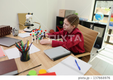 Young scientist explores molecular structures with colorful models in a bright, engaging study environment 137668976