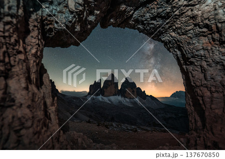 Rocky cave Grotta delle Tre Cime framing Tre Cime di Lavaredo mountain peaks with Milky Way in Dolomites, Italy Rocky cave Grotta delle Tre Cime framing Tre Cime di Lavaredo mountain peaks with Milky Way in Dolomites, Italy 137670850