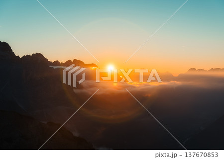 Golden sun halo glowing above alpine mountain peak in Dolomites, Italy 137670853