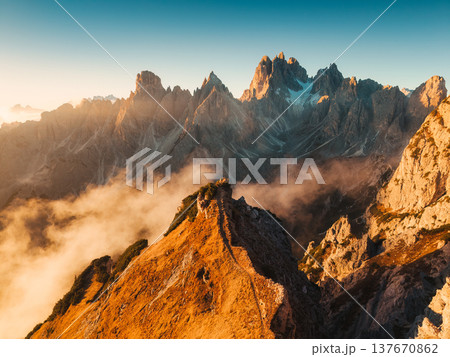 Scenic view of golden sunrise over rugged steep peaks of Cadini di Misurina with rising fog in Dolomites, Italy Scenic view of golden sunrise over rugged steep peaks of Cadini di Misurina with rising fog in Dolomites, Italy 137670862