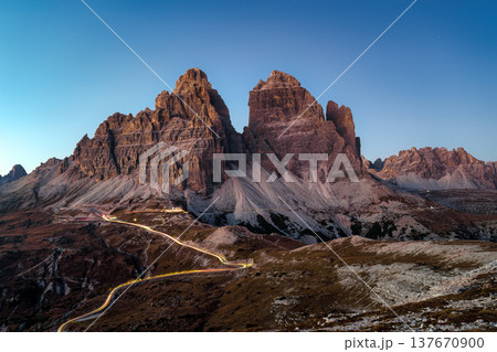 Scenery of Tre Cime di Lavaredo peak with light trail road in the dusk at Dolomites, Italy Scenery of Tre Cime di Lavaredo peak with light trail road in the dusk at Dolomites, Italy 137670900