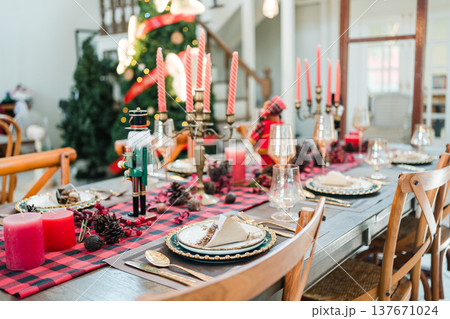 Festive christmas dining table with candles, pinecones, elegant tableware in cozy home interior 137671024