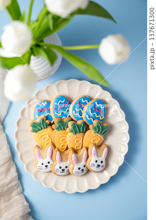Easter spring holiday background with easter cookies in a plate: bunny, carrot and egg with white tulips in a vase Easter spring holiday background with easter cookies in a plate: bunny, carrot and egg with white tulips in a vase 137671300