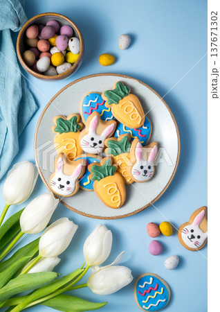 Easter spring holiday background with easter cookies in a plate: bunny, carrot and egg with white tulips 137671302