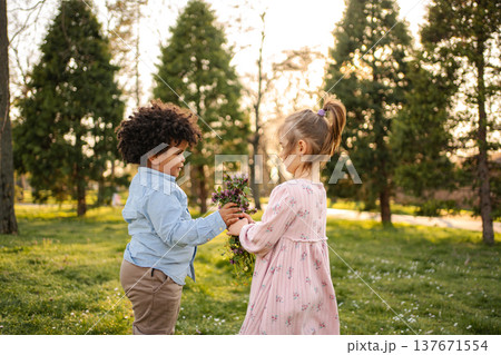 Little boy giving flowers to girl in park Little boy giving flowers to girl in park 137671554