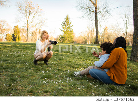 Woman photographer capturing mother and child interaction in park 137671562