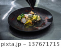 Exquisite seafood dish with salmon fillet broccoli and radish on a black designer plate 137671715